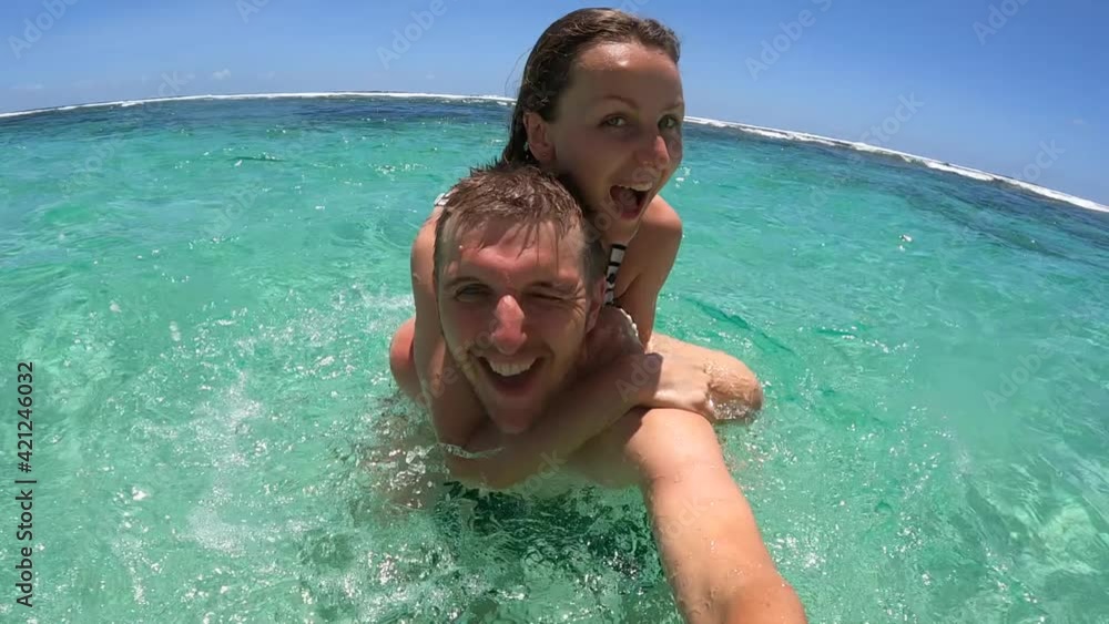 Romantic holidays concept. Young couple playing in an ocean looking to the camera Romantic holidays concept. Young couple playing in an ocean looking to the camera