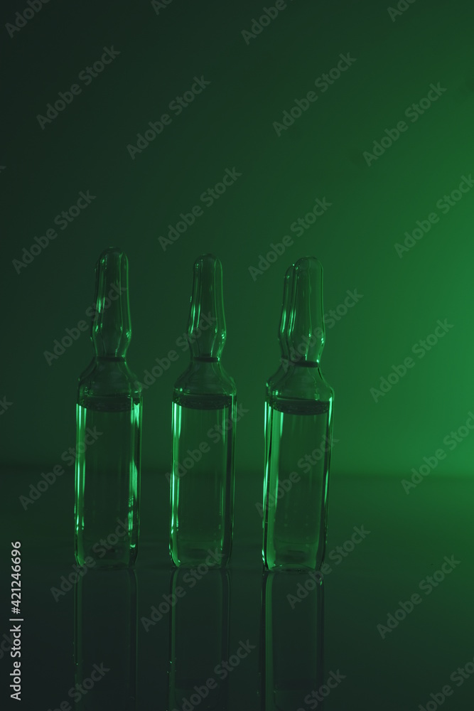Biotechnology and Science. Medicine and Pharmacology concept.Glass transparent ampoules  in green light.Organic natural cosmetics concept.Ampoules with solution for injection.Health and beauty