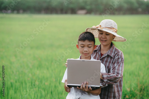 Children holding laptop and mother on rice field background
