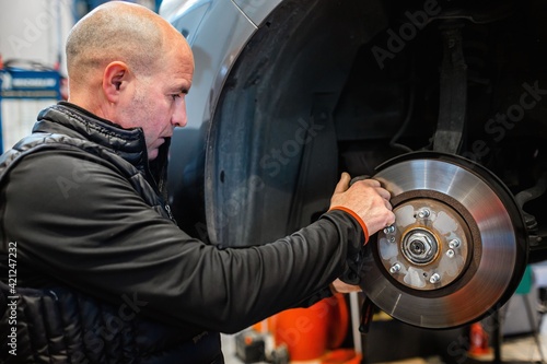 Mechanic in a car repair shop checking the brakes of a vehicle