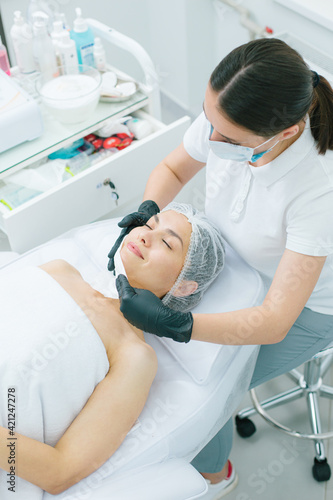 Relaxed woman closing her eyes during the pleasant skin treatment