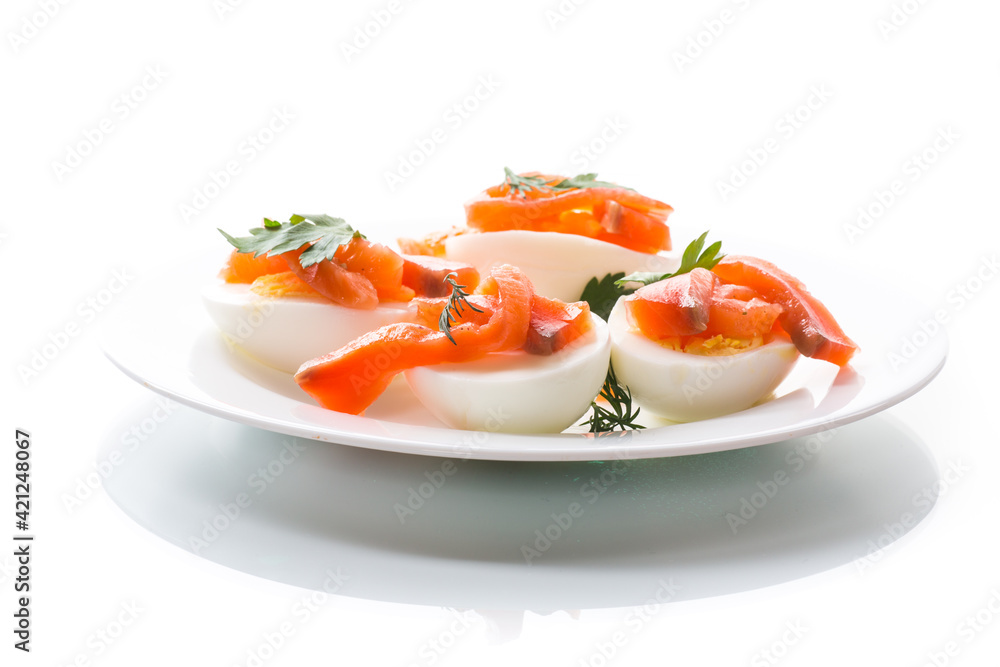 halves of boiled eggs with pieces of salted salmon on white background halves of boiled eggs with pieces of salted salmon on white background