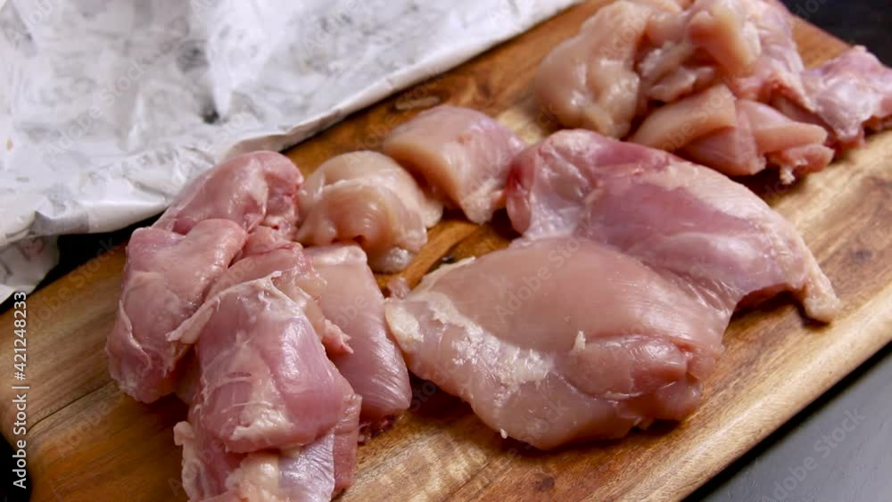 Woman's hands cut fresh chicken pieces on a wooden board close up Woman's hands cut fresh chicken pieces on a wooden board close up