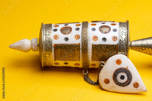 Upper part closeup of handhold small buddhist prayer mill. Studio religious tourist souvenir still life against a seamless yellow background. photo