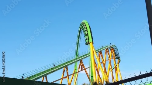 SLOW MOTION: Riddler's Revenge roller coaster in Six Flags Magic Mountain cresting the loop on a sunny day. photo