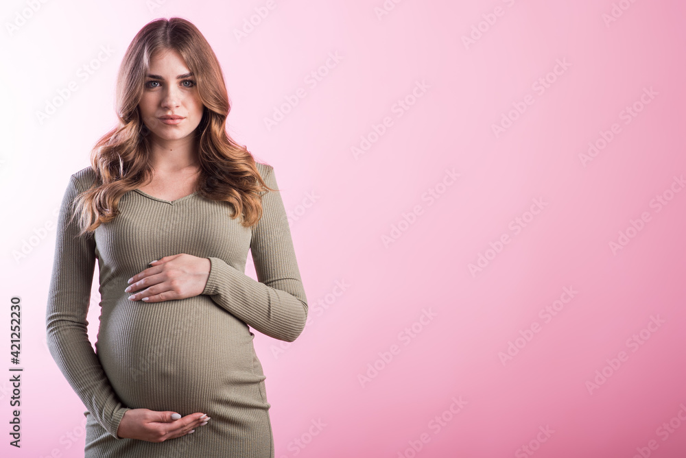 Portrait of a pregnant girl in the studio on a pink background with copyspace Portrait of a pregnant girl in the studio on a pink background with copyspace