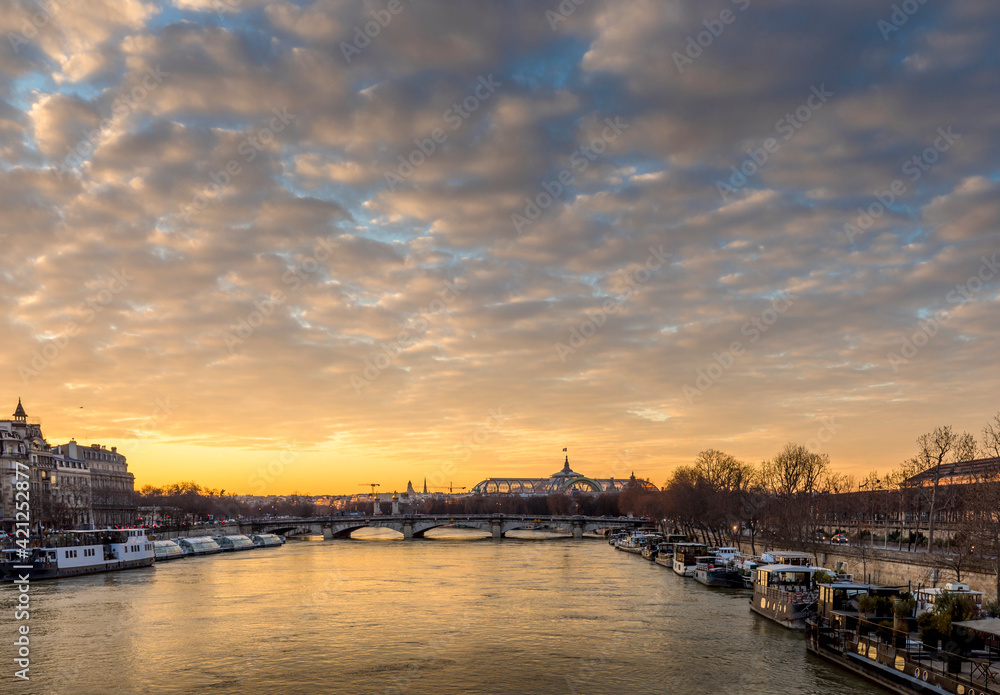 Paris, France - February 12, 2021: Seine river and Grand Palais in background with a beautiful cloudy sunset in Paris