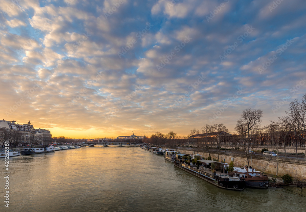 Naklejka premium Paris, France - February 12, 2021: Seine river and Grand Palais in background with a beautiful cloudy sunset in Paris