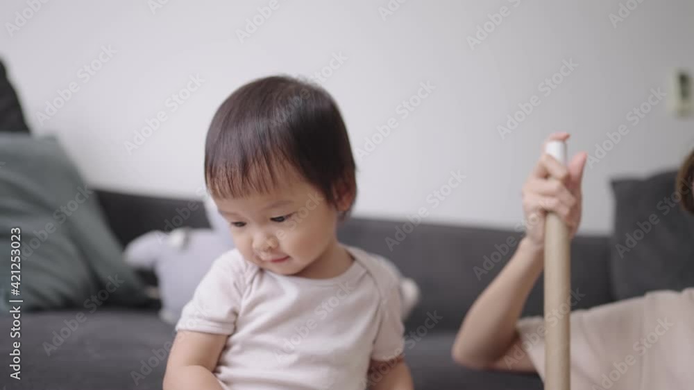 Active adorable female infant stays in nursery in daytime, cheerful preschooler standing in front of living room's sofa and playing alone next to her companion or babysitter, education homeschooling Active adorable female infant stays in nursery in daytime, cheerful preschooler standing in front of living room's sofa and playing alone next to her companion or babysitter, education homeschooling
