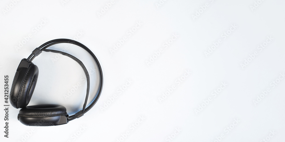 Black big headphones on a light blue background, top view. Wireless professional studio headphones, flat lay. Banner, copy space. Black big headphones on a light blue background, top view. Wireless professional studio headphones, flat lay. Banner, copy space.