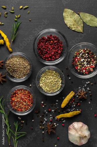 various spices on a gray background. seasoning in glass cups top view, close-up, vertical photo