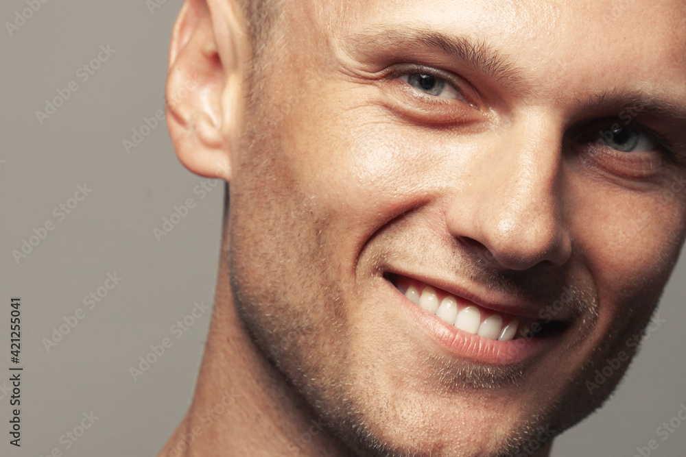 Male beauty concept. Portrait of handsome 30-year-old man with blue eyes posing over gray background. Close up. Classic style. Shiny white smile. Headshot. Studio shot