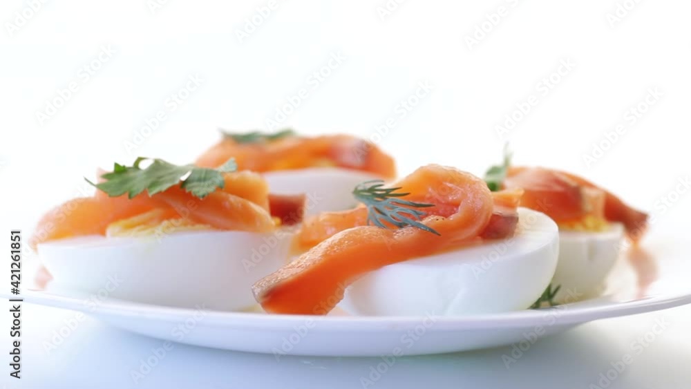 halves of boiled eggs with pieces of salted salmon on white background halves of boiled eggs with pieces of salted salmon on white background