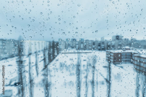 Obraz na płótnie Raindrops on the window with a view of the winter blue snow-covered city. The concept of depression and bad mood w salonie