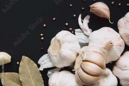 Garlic bulbs on a black background with spices, pepper and bay leaf. Natural antibiotics. Healthy food concept.