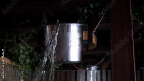 Bucket of cold water is tipped over in a hot sauna. Health concept, hardening of the body