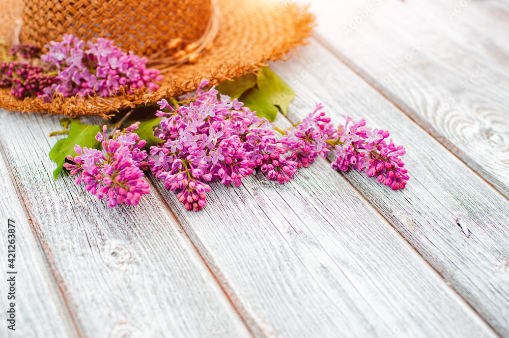spring lilac flowers and a straw hat on a white wooden background are a free place to insert text. minimalism, design, top view. flatley spring lilac flowers and a straw hat on a white wooden background are a free place to insert text. minimalism, design, top view. flatley