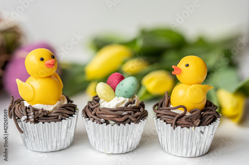 cute colorful spring easter egg shape cake tartlet muffin cupcake with yellow tulips easter concept  © Lumistudio