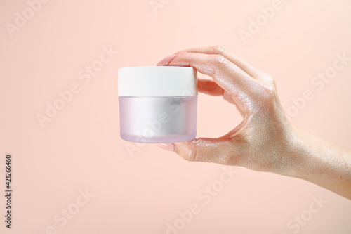 Close up shot of woman holding matt jar of moisturizing cream isolated on pink. Cosmetics concept