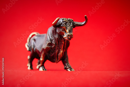 Bronze bull figurine on red background