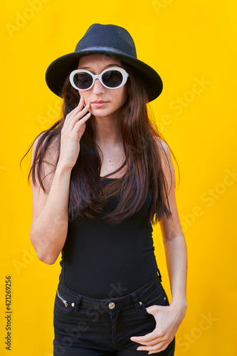 American flat vertical photo of a young caucasian woman on yellow background, hand over face