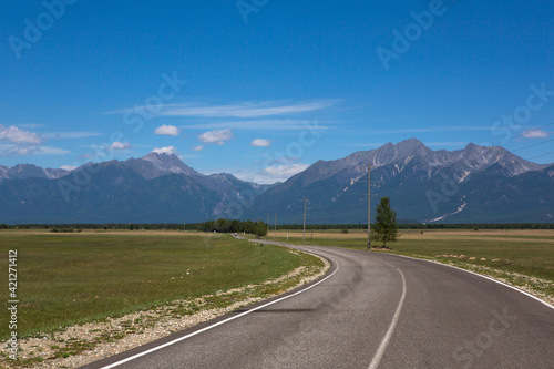 The road goes into the distance. Mountains in the background. Landscape with a horizon. Summer sunny day. Traveling around the country.