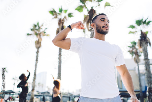 Confident young man showing power gesture after training outside
