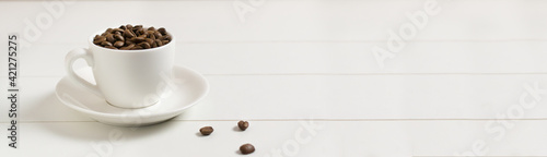 Banner Coffee beans in a white espresso cup with several beans on a white background. Morning coffee concept.