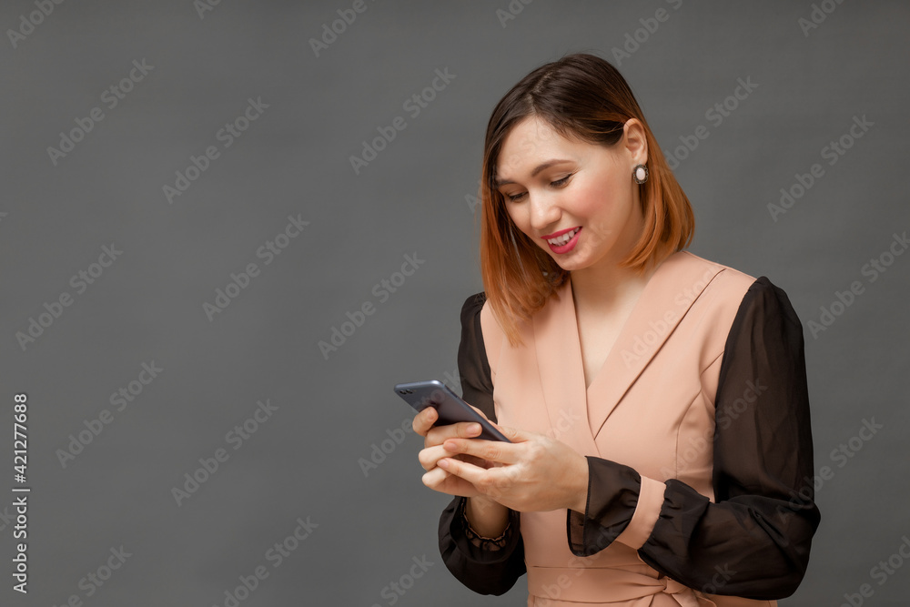 young smiling woman using mobile phone on gray background young smiling woman using mobile phone on gray background