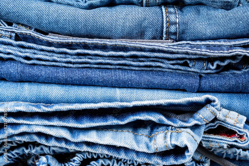 Neatly folded denim clothing. Background on the theme of jeans. Neatly folded denim clothing. Background on the theme of jeans.