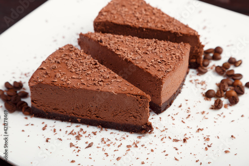 A piece of chocolate cake on a white plate on a wooden background