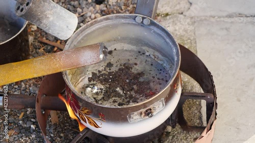 Dripping lead in bowl. Melting metal bar with torch fire. Melting lead (plumbum) or alumnium stick with burner fire photo