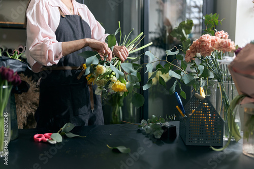 Photo of florist holding beautiful flowers in flower shop, copy space. Lifestyle flower shop. Beautiful flower composition photo