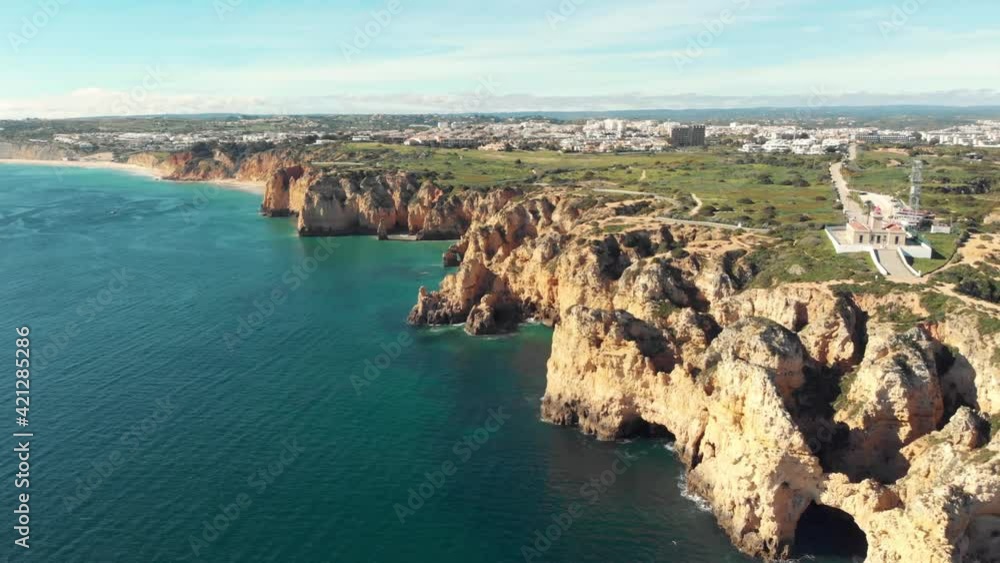 overlooking lighthouse over clifftop lining Ponta da Piedade coastline, Lagos, Algarve - Wide Aerial fly-over shot overlooking lighthouse over clifftop lining Ponta da Piedade coastline, Lagos, Algarve - Wide Aerial fly-over shot