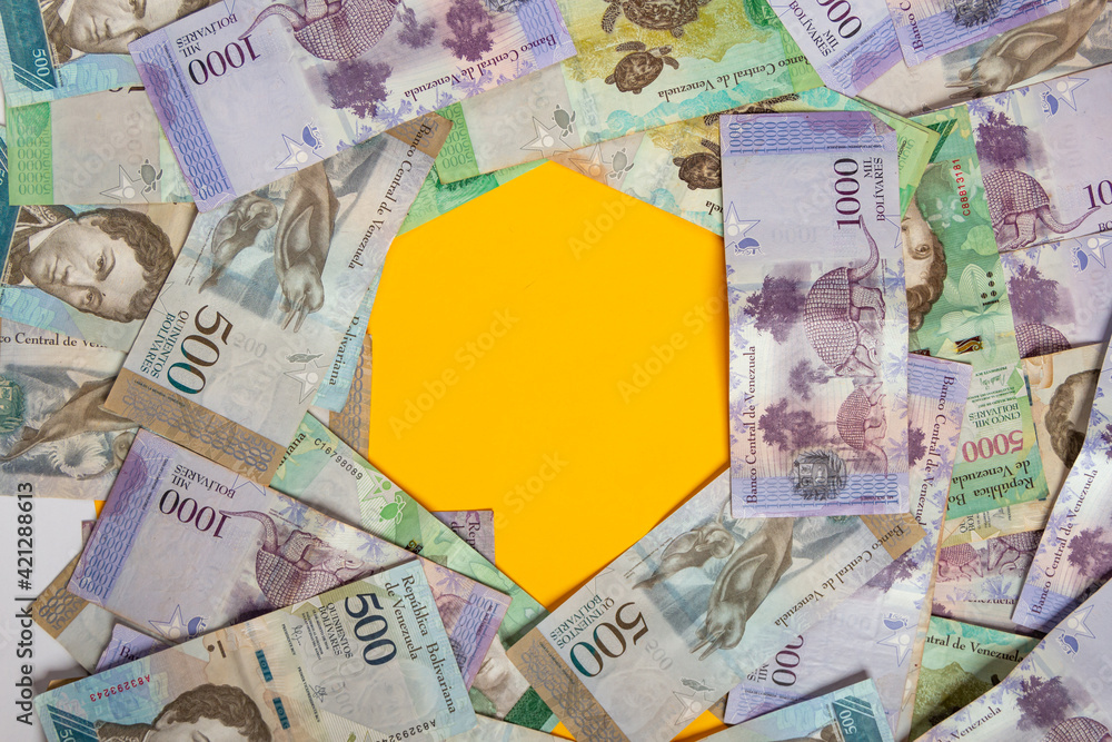 montones de dinero venezolano a la vista superior uno encima del otro con números de 500 y 1000 bolívares con un espacio de fondo amarillo, vista superior.