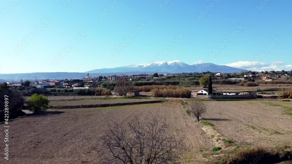 Drone aerial view of Moncayo snow mountain in Spain flying straight on across farms