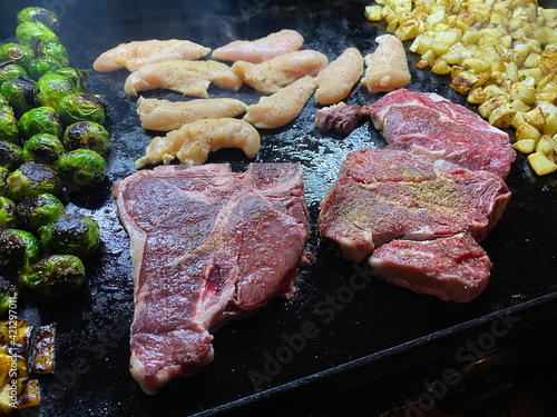 Steak and potatoes and veggies on a stone grill