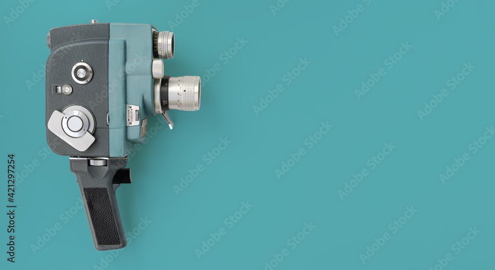 Fototapeta premium Vintage 8mm camera with 8mm reel on blue background.