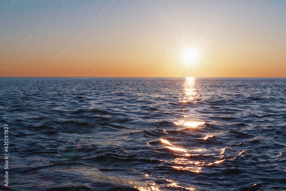 The setting sun goes into the sea on the horizon with a light track and reflections on the sea. The setting sun goes into the sea on the horizon with a light track and reflections on the sea.