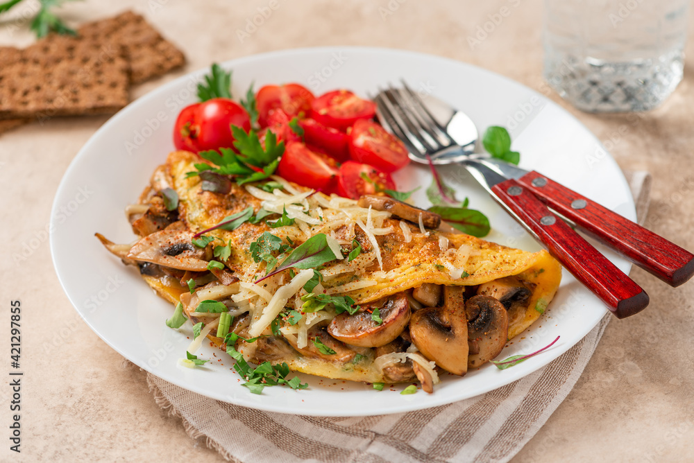 Omelet with mushrooms close-up. Tasty breakfast or lunch. Omelet with champignons, cheese, and tomatoes in a white plate on the table. Omelet with mushrooms close-up. Tasty breakfast or lunch. Omelet with champignons, cheese, and tomatoes in a white plate on the table.