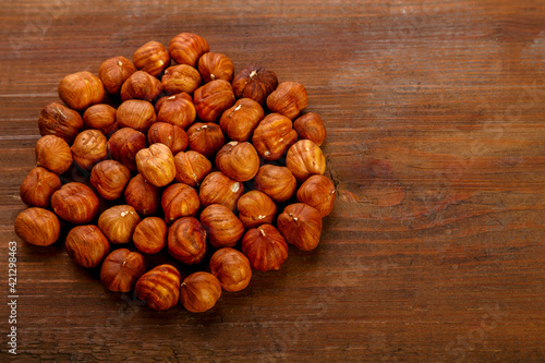 Hazelnuts are scattered on a dark wooden table.