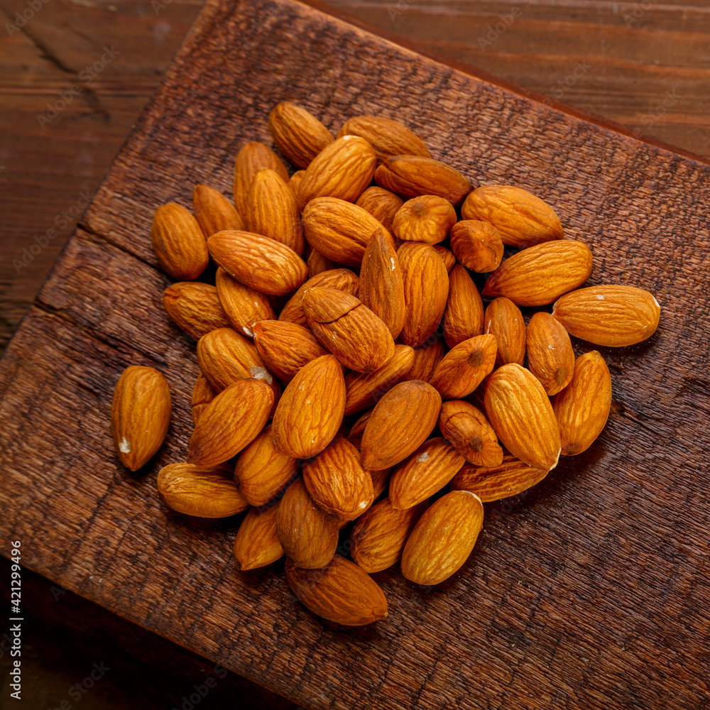 A handful of nuts are scattered on a board on a wooden table. A handful of nuts are scattered on a board on a wooden table.