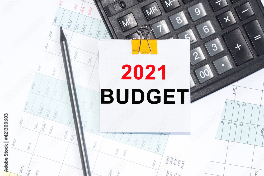 Text 2021 BUDGET on NOTEBOOK. NOTEBOOK, CALCULATOR PENCIL on white background. Text 2021 BUDGET on NOTEBOOK. NOTEBOOK, CALCULATOR PENCIL on white background.