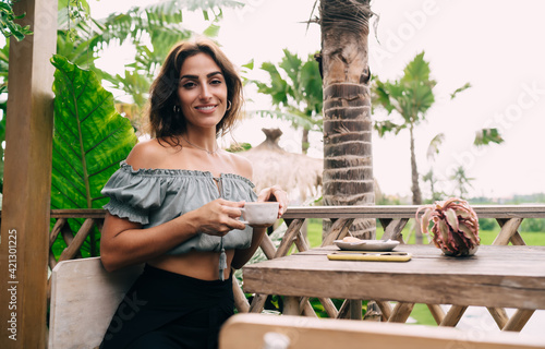 Young ethnic woman with coffee in outdoor cafe
