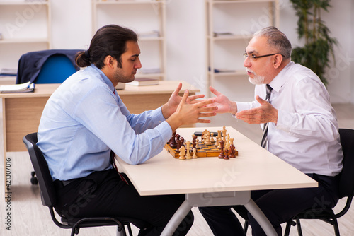 Two businessmen playing chess in the office