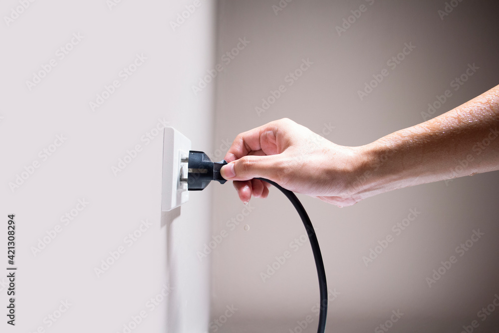 Foto de Wet hand connecting electrical plug cause electric shock, Idea