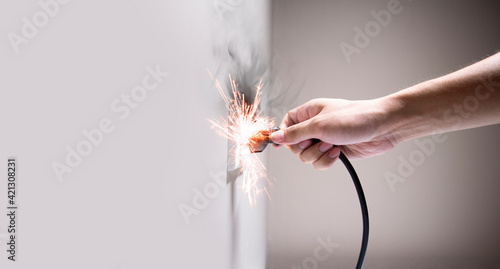 Hand connecting electrical plug cause electric shock, Idea for causes of home fire, Electric short circuit, Electrical hazard can ignite household items