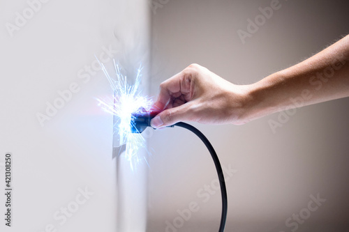 Hand connecting electrical plug cause electric shock, Idea for causes of home fire, Electric short circuit, Electrical hazard can ignite household items