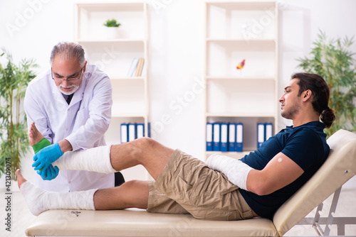 Young injured man visiting old doctor traumatologist