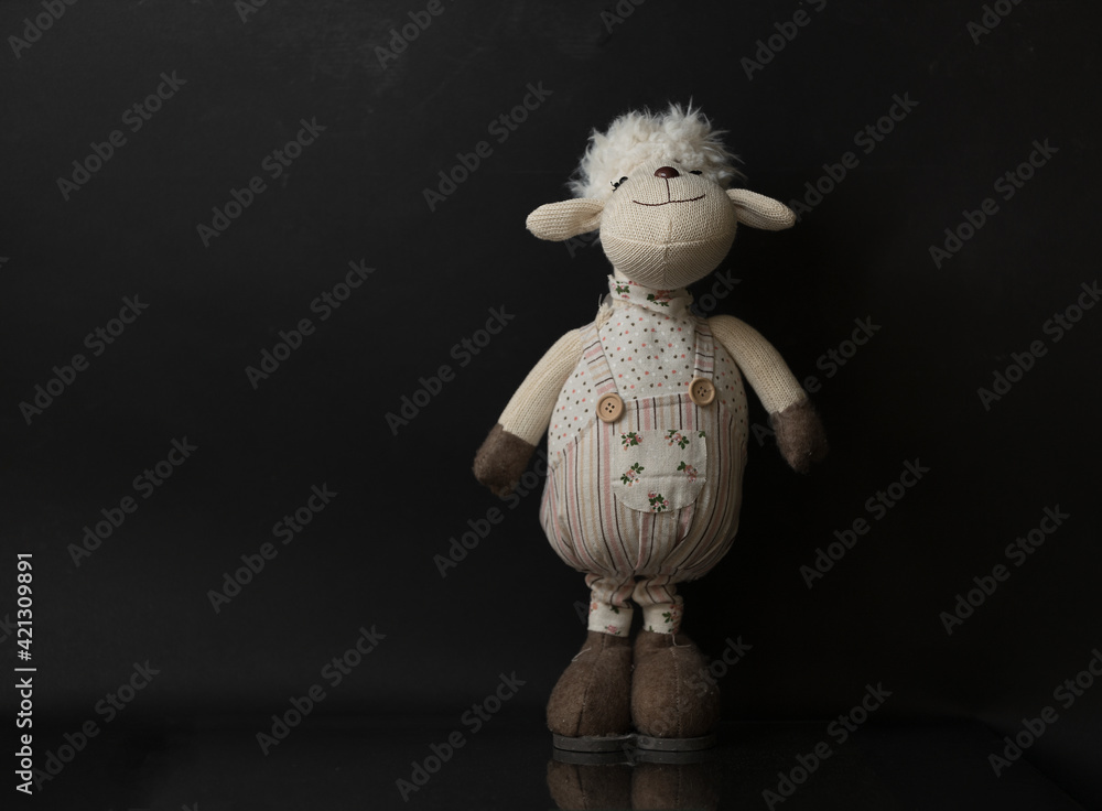 samotna owieczka maskotka na czarny tle z delikatnym odbiciem - obrazy, fototapety, plakaty 